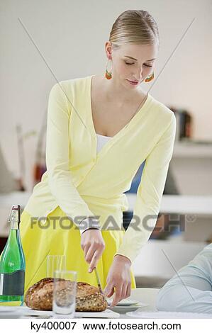 Woman cutting bread at the dining table View Large Photo Image Stock Photo - Woman cutting bread at the dining table. Fotosearch