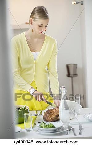 Stock Photo - Woman cutting bread for dinner. Fotosearch
