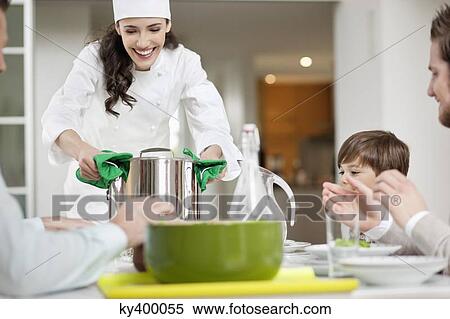 Stock Photography - Woman serving food to her family. Fotosearch