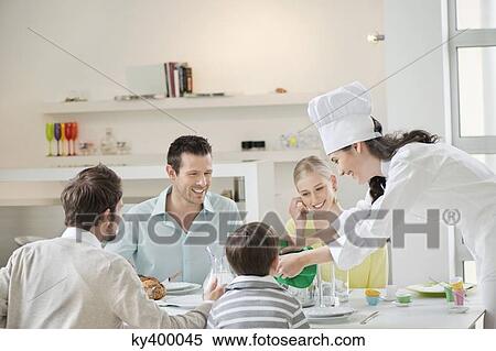 Stock Photography - Woman serving lunch at dining table. Fotosearch