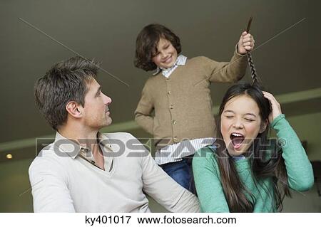 Boy pulling his sister's braid with his father looking at him View Large Photo Image Stock Photo - Boy pulling his sister's braid with his father looking at him. Fotosearch