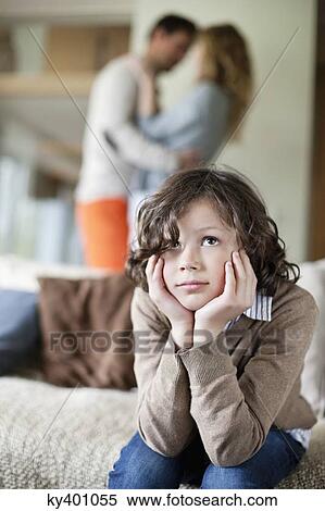 Stock Photography - Boy sitting on a couch with his parents romancing in the background. Fotosearch