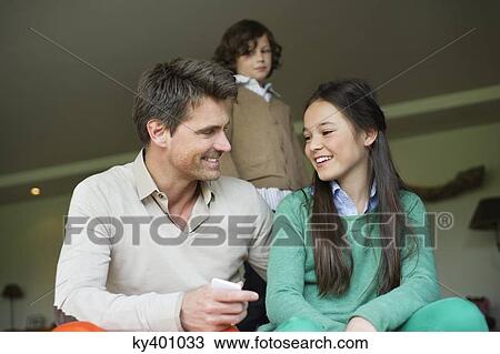 Stock Image - Man sitting with his daughter at home. Fotosearch