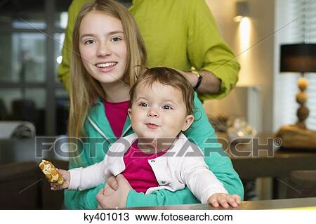 Stock Image - Portrait of two girls with their father at home. Fotosearch