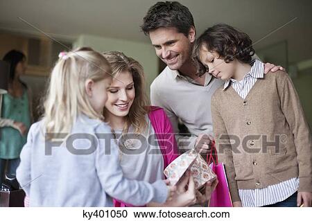 Stock Image - Woman looking at gift with her family at Mother's Day party at home. Fotosearch
