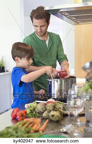 Boy assisting his father in the kitchen View Large Photo Image Stock Photo - Boy assisting his father in the kitchen. Fotosearch