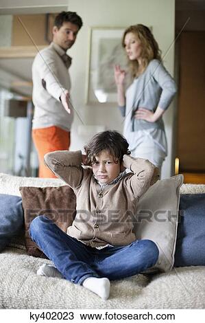 Boy covering ears with hands while his parents arguing in the background View Large Photo Image Stock Image - Boy covering ears with hands while his parents arguing in the background. Fotosearch