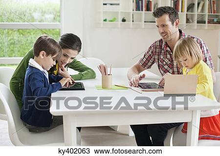 Stock Image - Couple teaching their children at home. Fotosearch