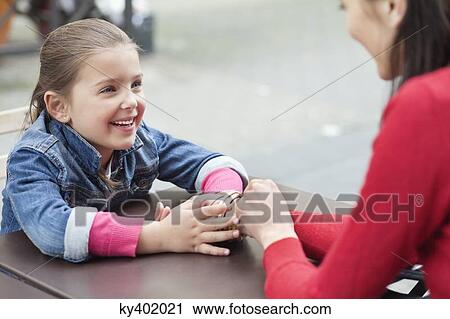 Girl sitting with her mother at a sidewalk cafe View Large Photo Image Stock Image - Girl sitting with her mother at a sidewalk cafe. Fotosearch