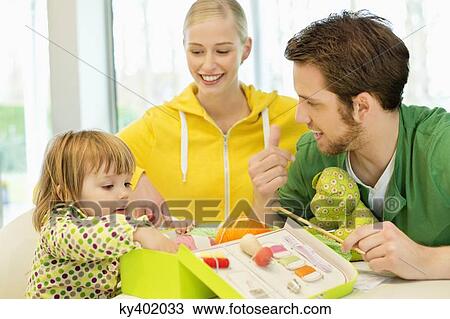 Girl sitting with her parents looking into a knitting kit box View Large Photo Image Stock Image - Girl sitting with her parents looking into a knitting kit box. Fotosearch