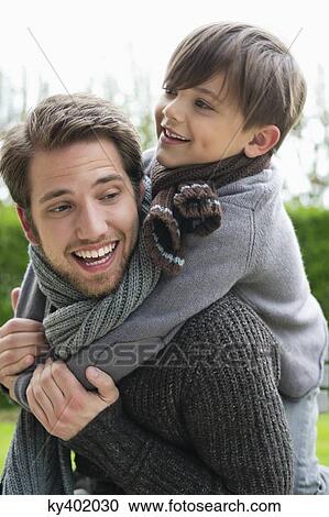 Happy boy riding piggyback on his father View Large Photo Image Stock Image - Happy boy riding piggyback on his father. Fotosearch