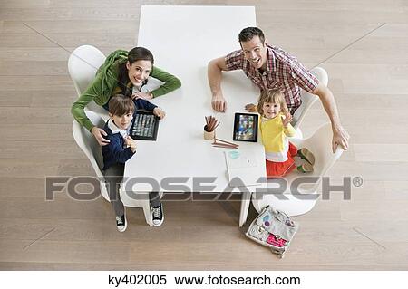 Stock Photography - High angle view of couple with their children at study table. Fotosearch
