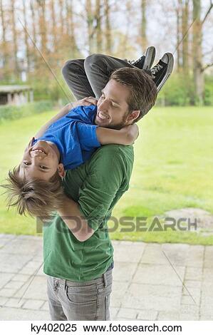 Man playing with his son in a park View Large Photo Image Stock Photography - Man playing with his son in a park. Fotosearch