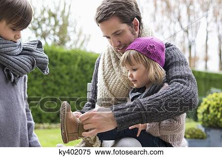 Stock Photography - Man putting on shoe to his daughter. Fotosearch