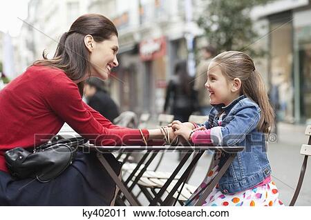 Woman and her daughter sitting at sidewalk cafe View Large Photo Image Stock Image - Woman and her daughter sitting at sidewalk cafe. Fotosearch