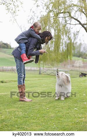 Woman carrying her daughter on piggyback and scolding her dog View Large Photo Image Stock Image - Woman carrying her daughter on piggyback and scolding her dog. Fotosearch