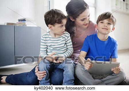 Stock Image - Woman looking at her son using a digital tablet. Fotosearch