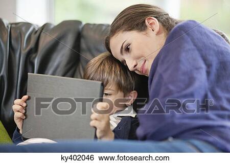 Woman looking at her son using a digital tablet View Large Photo Image Stock Photograph - Woman looking at her son using a digital tablet. Fotosearch