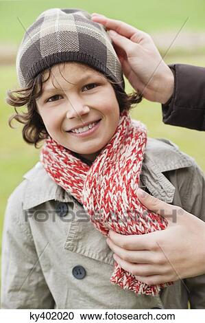 Stock Image - Woman putting on warm clothing on her son. Fotosearch