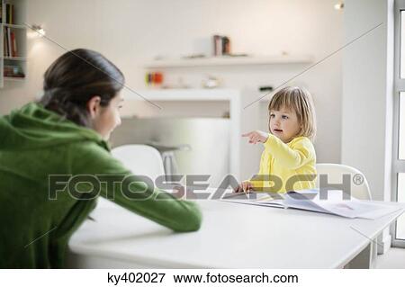Woman teaching her daughter at home View Large Photo Image Stock Photo - Woman teaching her daughter at home. Fotosearch