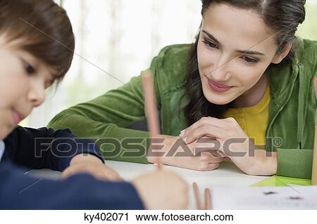 Stock Image - Woman teaching her son at home. Fotosearch