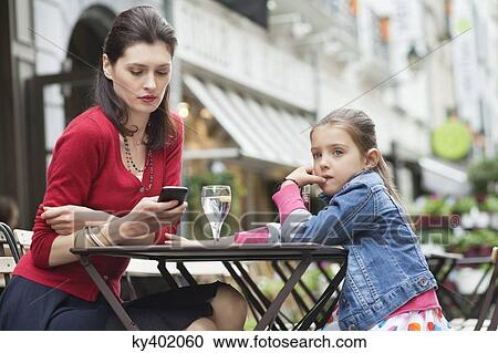 Woman with her daughter sitting in a cafe View Large Photo Image Stock Image - Woman with her daughter sitting in a cafe. Fotosearch