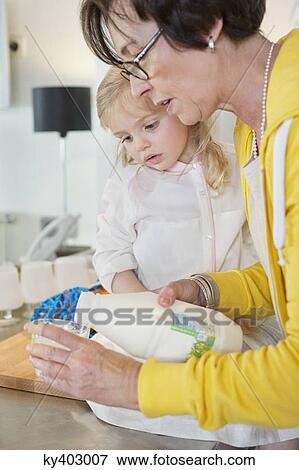 Elderly woman pouring milk into a glass for her granddaughter View Large Photo Image Stock Photo - Elderly woman pouring milk into a glass for her granddaughter. Fotosearch