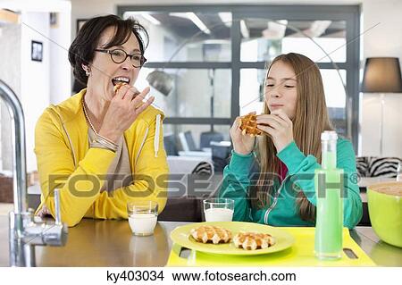 Elderly woman with her granddaughter eating waffles View Large Photo Image Picture - Elderly woman with her granddaughter eating waffles. Fotosearch