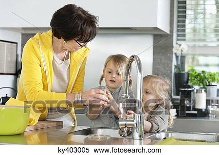 Stock Photography - Elderly woman with her granddaughters washing in a kitchen. Fotosearch