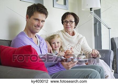 Stock Image - Girl studying with her father and grandmother at home. Fotosearch