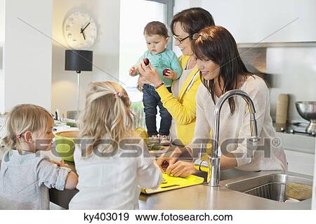 Stock Photo - Girls with her mother and grandmother in a kitchen. Fotosearch