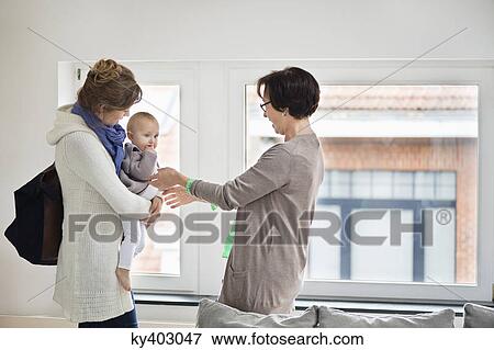 Stock Photo - Nanny taking a baby girl from her mother. Fotosearch
