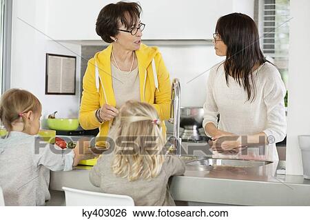 Two girls with her mother and grandmother discussing in a kitchen View Large Photo Image Stock Photograph - Two girls with her mother and grandmother discussing in a kitchen. Fotosearch