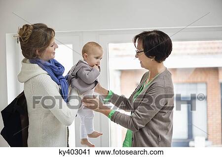 Woman giving her daughter to nanny View Large Photo Image Stock Image - Woman giving her daughter to nanny. Fotosearch