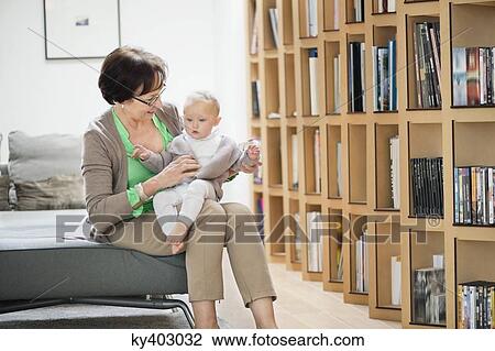 Stock Image - Woman sitting on a couch playing with her granddaughter. Fotosearch