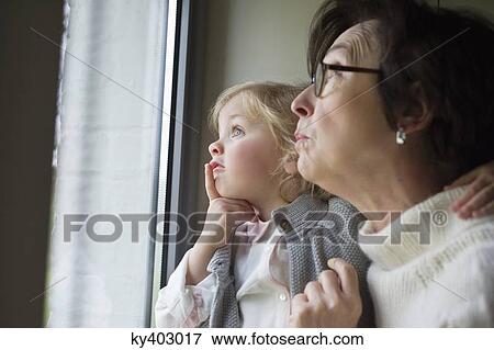 Stock Photo - Woman with her granddaughter looking through a window. Fotosearch