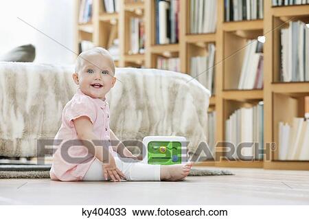 Stock Image - Baby girl playing with a musical block toy. Fotosearch