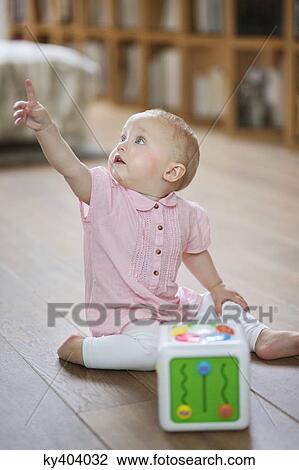 Baby girl sitting on the floor and pointing away with finger View Large Photo Image Stock Image - Baby girl sitting on the floor and pointing away with finger. Fotosearch