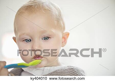 Close-up of a baby girl holding a spoon View Large Photo Image Stock Image - Close-up of a baby girl holding a spoon. Fotosearch