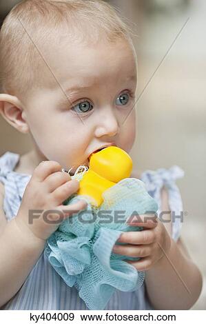 Stock Photo - Close-up of a baby girl playing with a toy. Fotosearch