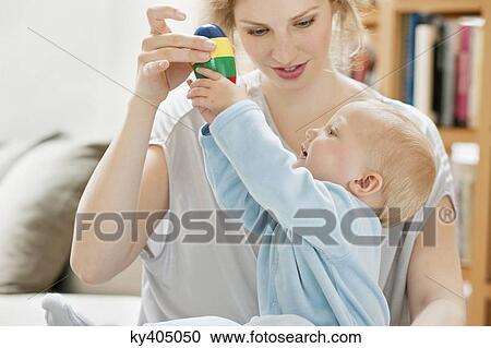 Baby girl playing with a toy held by her mother View Large Photo Image Stock Image - Baby girl playing with a toy held by her mother. Fotosearch