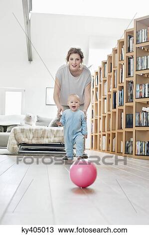 Woman playing with her daughter walking towards a ball View Large Photo Image Stock Image - Woman playing with her daughter walking towards a ball. Fotosearch