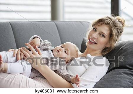 Woman resting on a couch with her daughter View Large Photo Image Stock Image - Woman resting on a couch with her daughter. Fotosearch