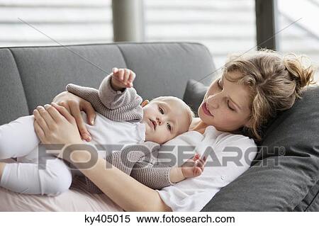 Woman resting on a couch with her daughter View Large Photo Image Stock Photography - Woman resting on a couch with her daughter. Fotosearch