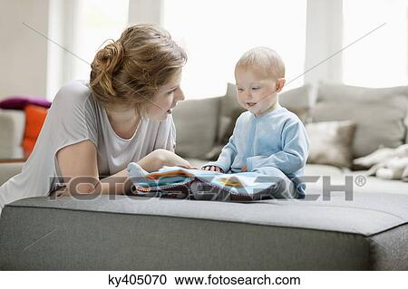 Stock Image - Woman showing a picture book to her daughter. Fotosearch