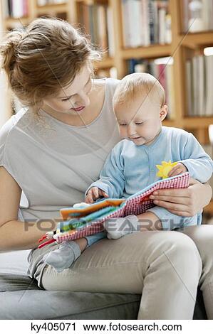 Stock Image - Woman showing a picture book to her daughter. Fotosearch