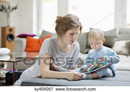 Stock Photo - Woman showing a picture book to her daughter. Fotosearch