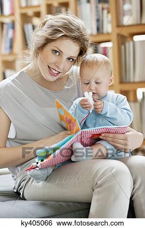 Woman showing a picture book to her daughter View Large Photo Image Stock Photograph - Woman showing a picture book to her daughter. Fotosearch