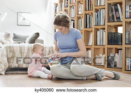 Woman sitting near her daughter playing with a toy View Large Photo Image Stock Image - Woman sitting near her daughter playing with a toy. Fotosearch