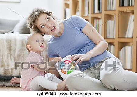 Woman sitting near her daughter playing with a toy View Large Photo Image Stock Photo - Woman sitting near her daughter playing with a toy. Fotosearch